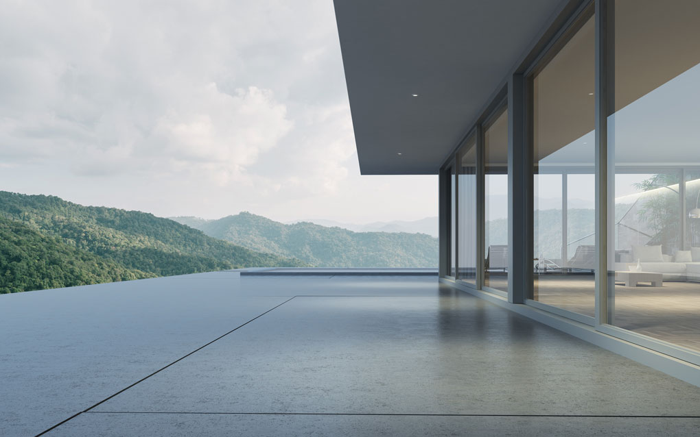 moderne Betonterrasse, rechtsseitig begrenzt durch die große Glasfront des Wohnbereichs
